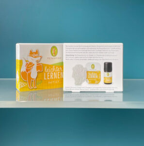 Die Vorder- und Rückseite der Primavera ‚Leichter lernen‘ Duftset-Verpackung mit Produktbeschreibung, Anwendungshinweisen und Inhaltsstoffen auf einem Glasregal.